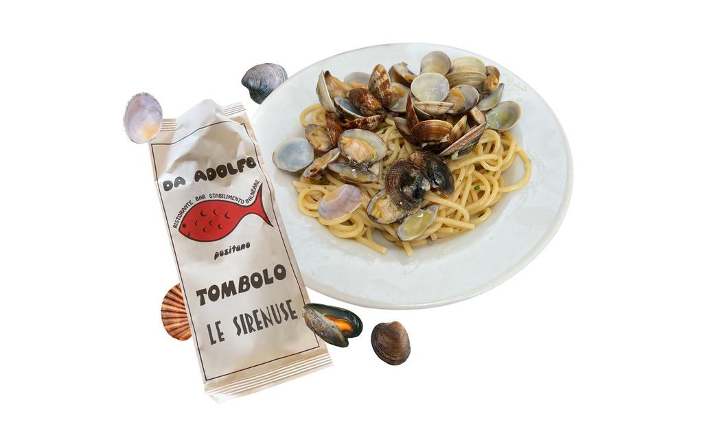 Tombolo Da Adolfo and Le Sirenuse names printed on cutlery bag next to a plate of spaghetti alle vongole 