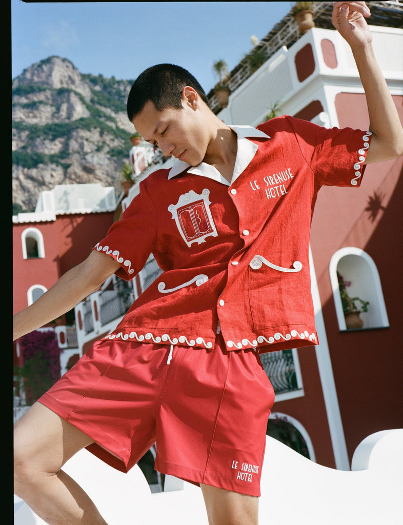 Man dances in matching finestra set with the inspired red walls of Le Sirenuse hotel in the background
