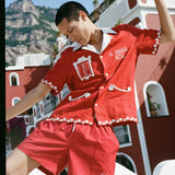 Man poses on one leg looking at the floor wearing matching red Le Sirenuse cabana set