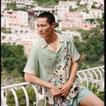 Man leans on balcony and looks off camera 