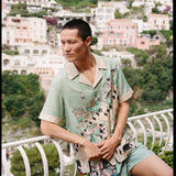 Man leans on balcony and looks off camera 