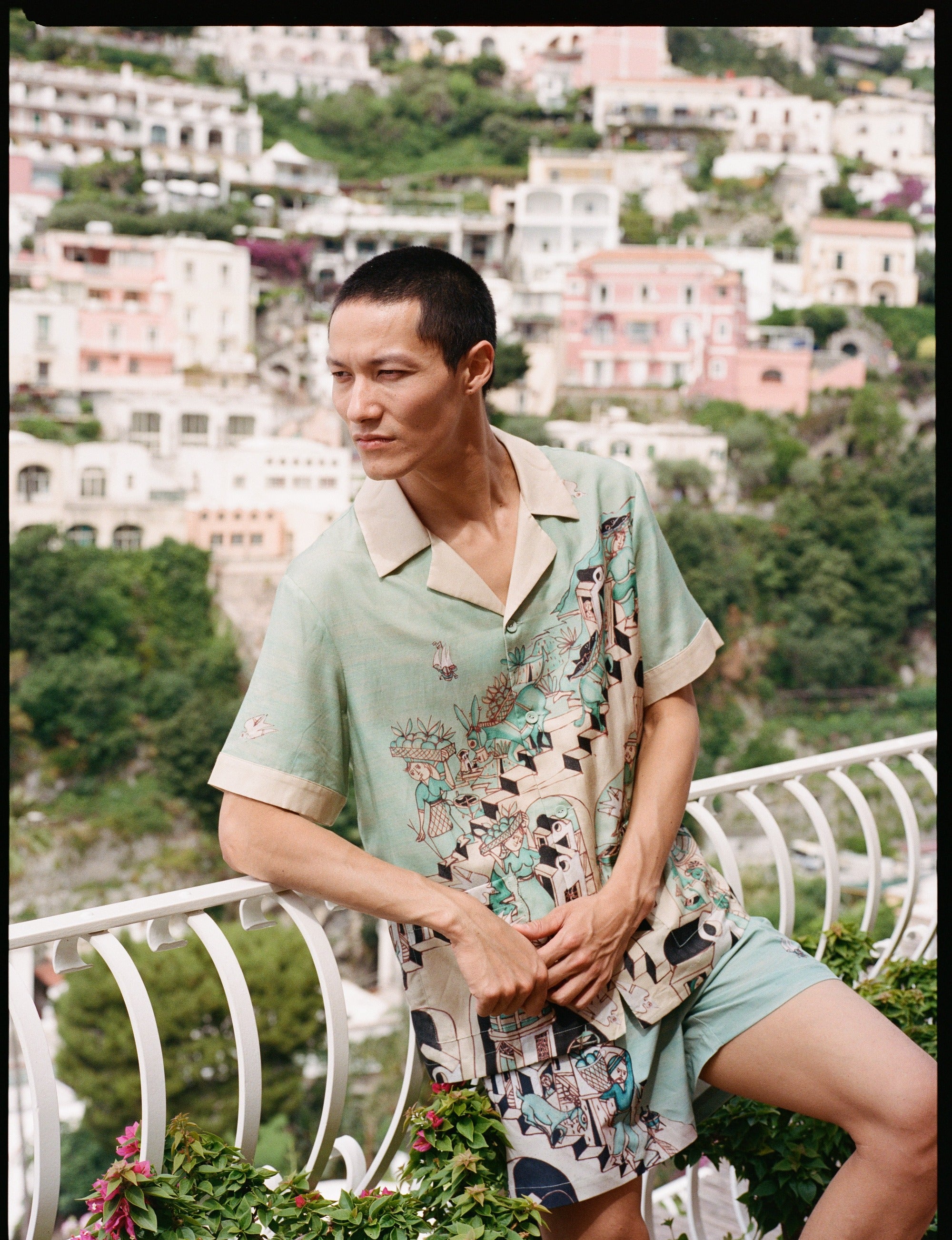 Man leans on balcony and looks off camera 