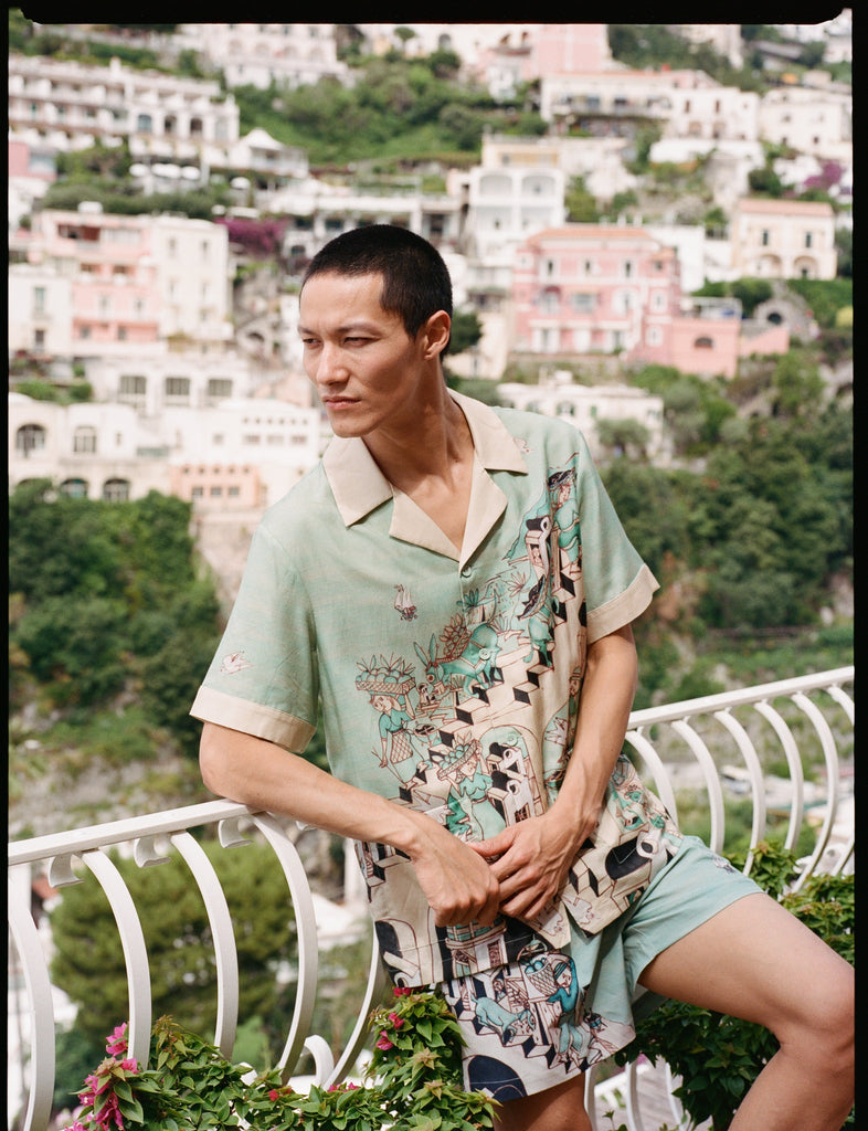 Man leans on balcony and looks off camera 