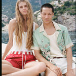 man and woman staring at the camera on a boat with the positano landscape in the background