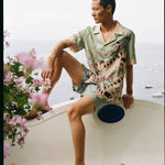 Male model wearing full set sitting along a wall with his leg up