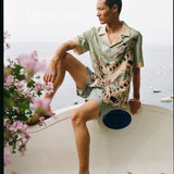 Male model wearing full set sitting along a wall with his leg up