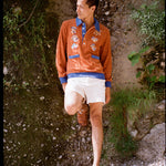 male model standing in disco fungi cabana and stowaway shorts leaning on a natural wall