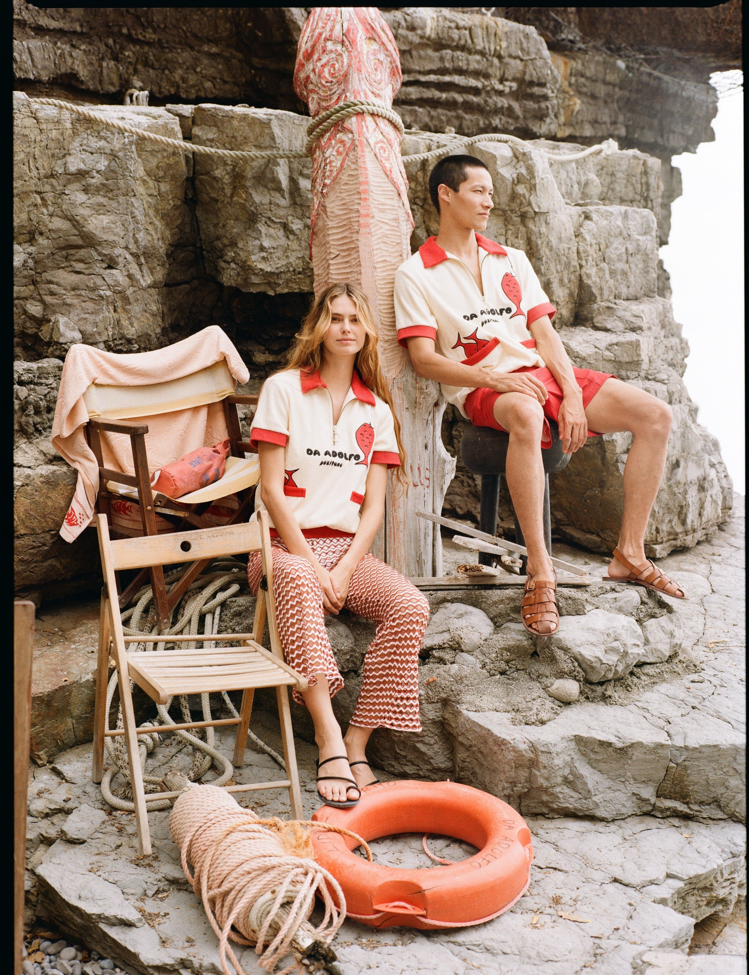 Man and woman sitting on rocks wearing matching Da Adolfo shirts
