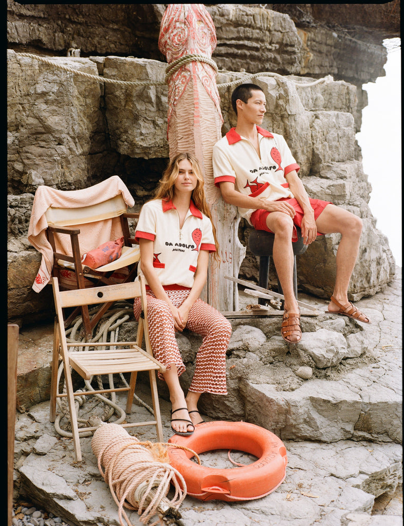 Man and woman sitting on rocks wearing matching Da Adolfo shirts