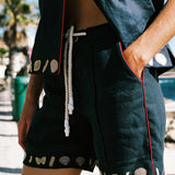 cropped image of woman wearing vongole linen shorts with hanging drawstring and half unbuttoned crop cut matching shirt