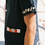 Close up of right sleeve on male model showing the pasta and shell embroidery