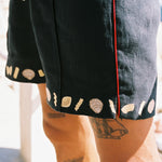 Close up of man wearing vongole linen shorts with tattoos showing on his legs