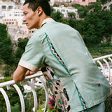 Man leans over balcony looking out onto the ocean in the Tombolo Liguori silk set