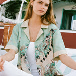Female model wearing shirt unbuttoned over an all white outfit