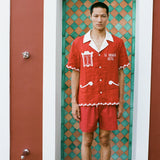 Man wearing red Le Sirenuse matching set standing in green tiled shower