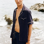 close up of man staring at camera wearing Cabrisa swim trunks with matching open button Cabrisa shirt