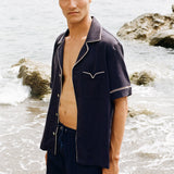 close up of man staring at camera wearing Cabrisa swim trunks with matching open button Cabrisa shirt