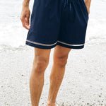 Close up of man wearing Cabrisa swim trunks standing ankle deep in the ocean
