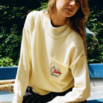 Woman sits on boat leaning forward while looking at camera