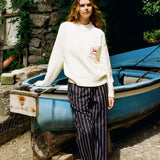 Woman wearing sweater leaning against blue boat