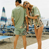 Woman leans on Man's shoulder smiling at the camera, wearing matching shirts and swim trunks