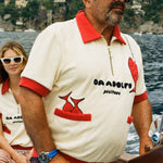 Man wearing baseball cap driving a boat while wearing the Tombolo Da Adolfo shirt