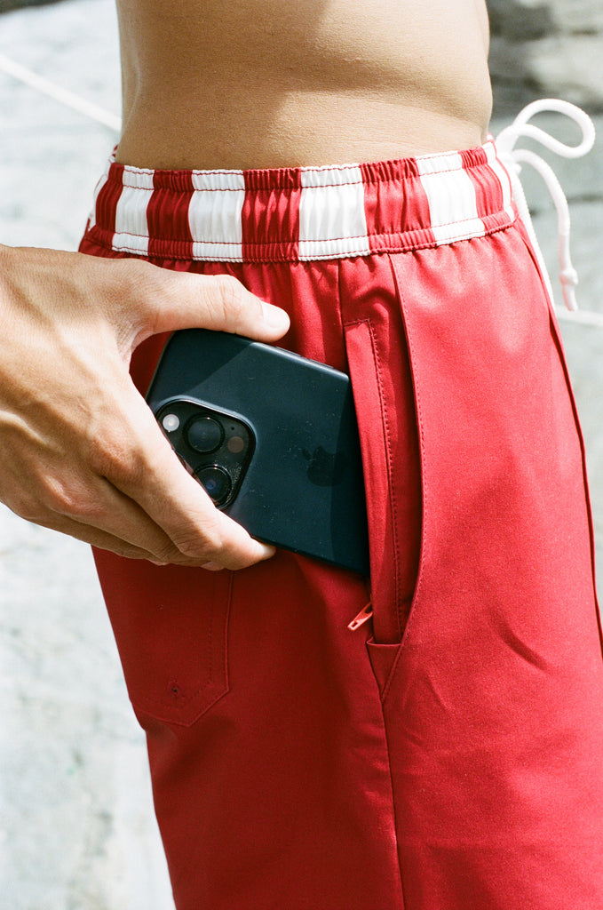 Man puts iphone in hidden zippered pocket of red swim trunks