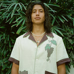 Male model standing in front of palm tree wearing 'Tombarolo' linen cabana shirt