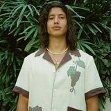 Male model standing in front of palm tree wearing 'Tombarolo' linen cabana shirt