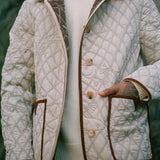 Hand inside pocket of off white reversible jacket