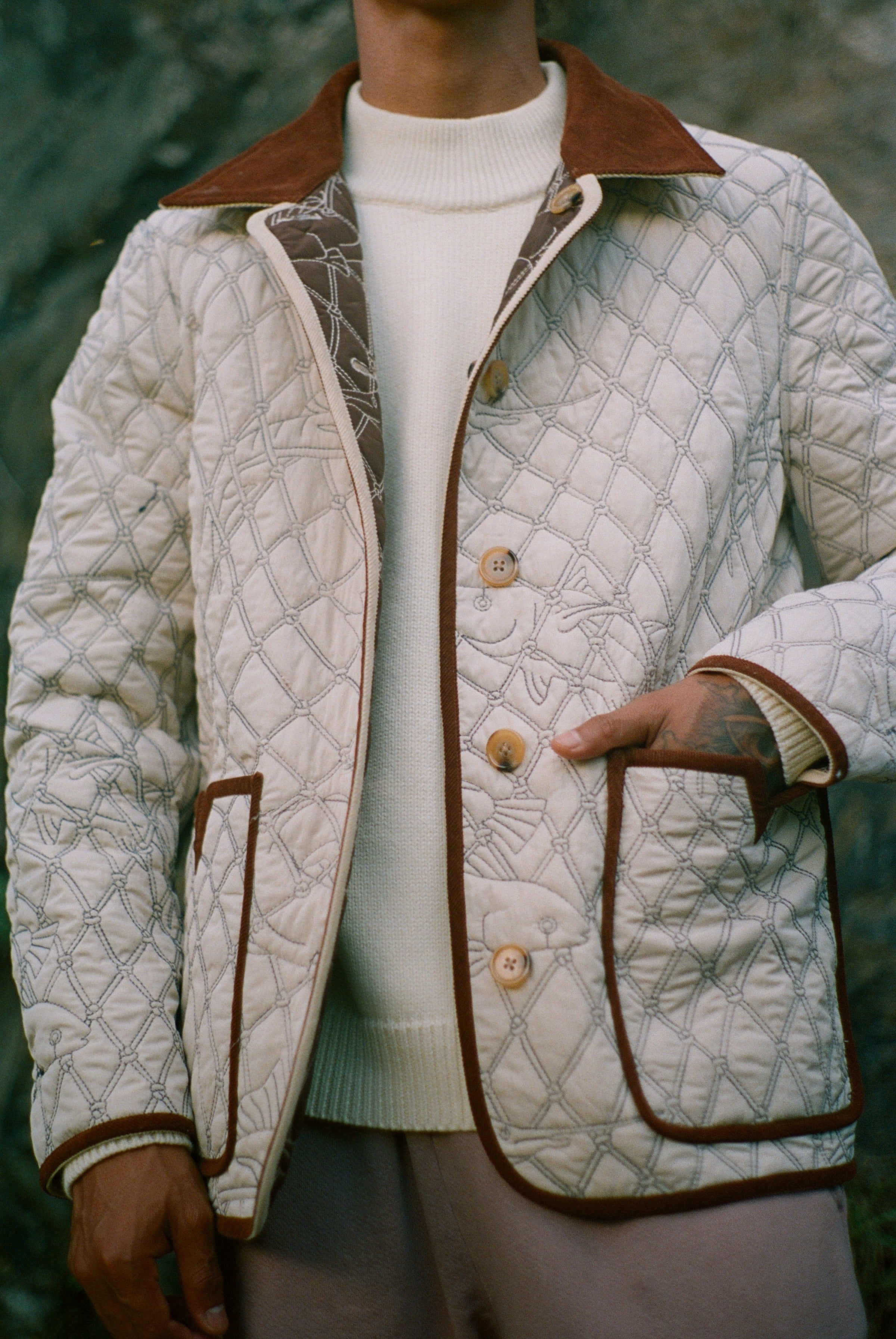 Hand inside pocket of off white reversible jacket