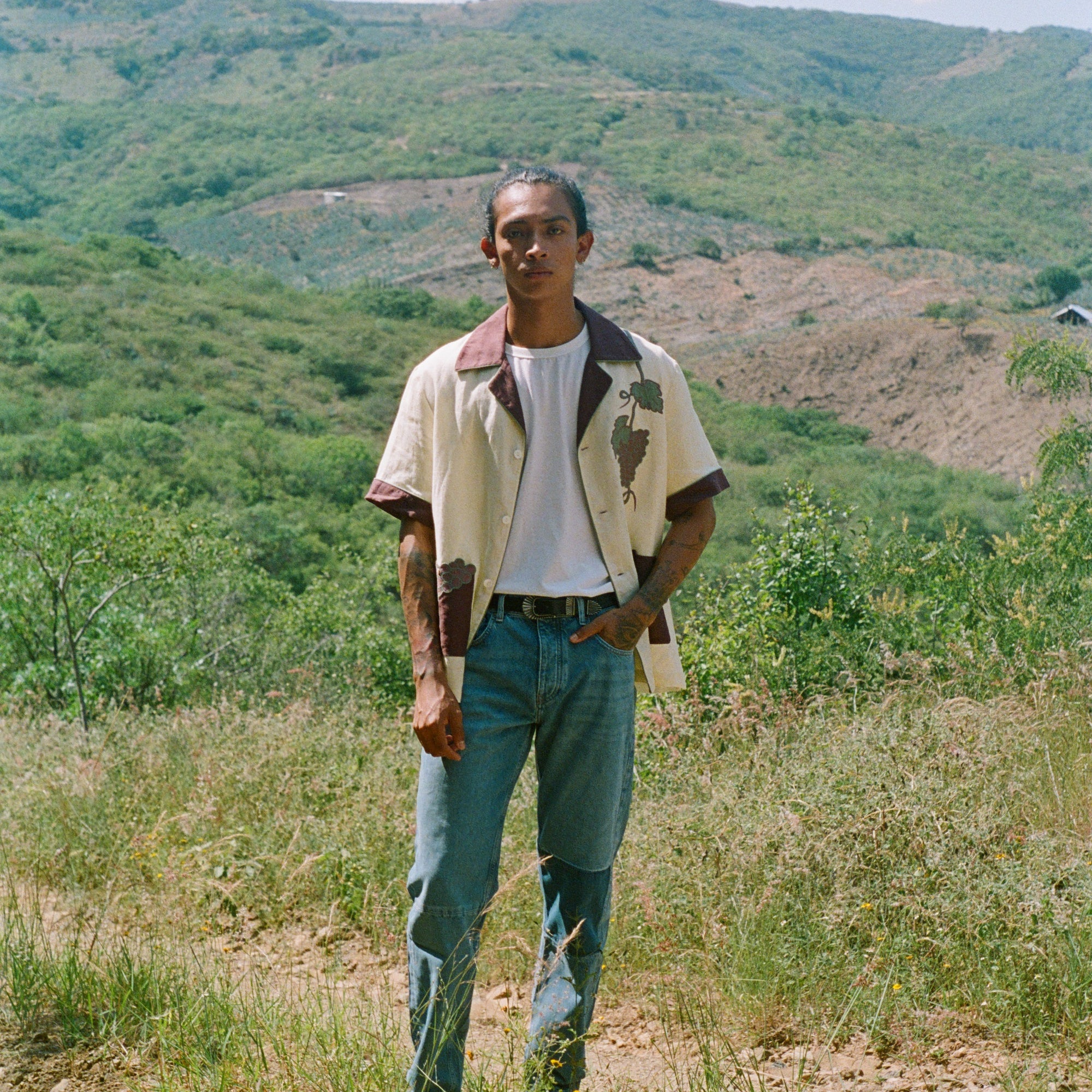Male model wearing 'Tombarolo' cabana shirt unbuttoned over t-shirt with jeans