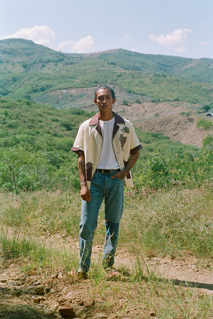 Male model wearing 'Tombarolo' cabana shirt unbuttoned over t-shirt with jeans