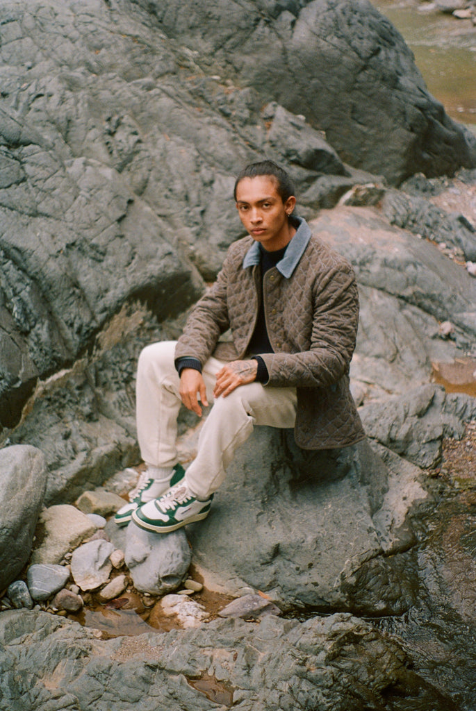 Man sits on rock in quilted jacket