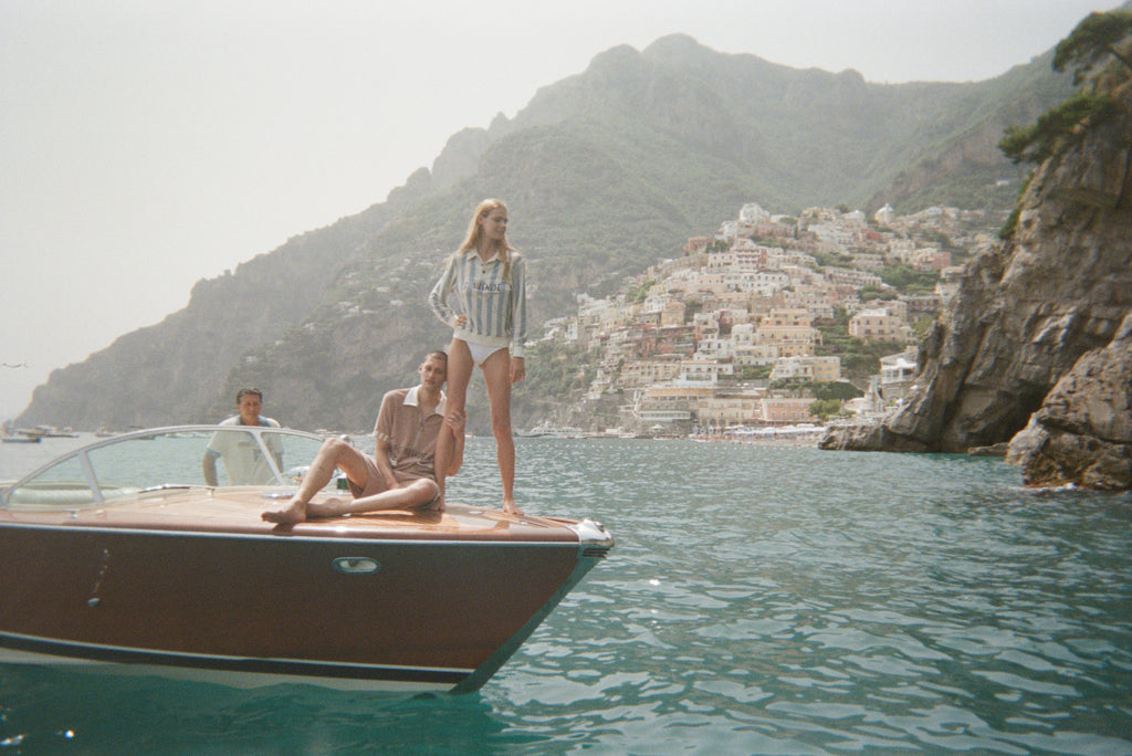 Man and woman on the front of speedboat with Positano in background