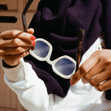 woman holding sunglasses to reveal inside of beige horned acetate interior