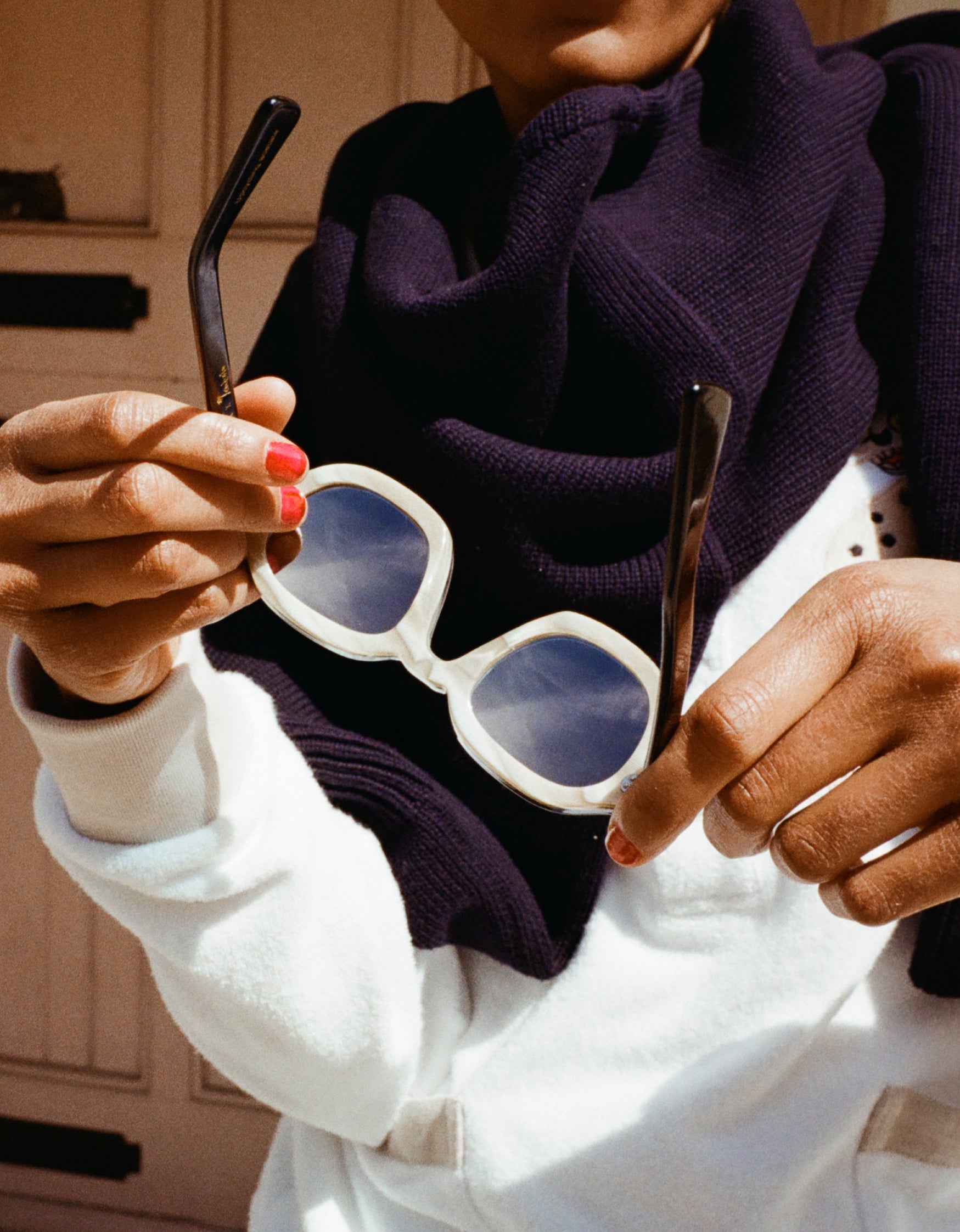 woman holding sunglasses to reveal inside of beige horned acetate interior