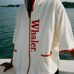 Close-up of woman wearing the white hooded beach towel top with red trim and vertical 'Whaler' text.