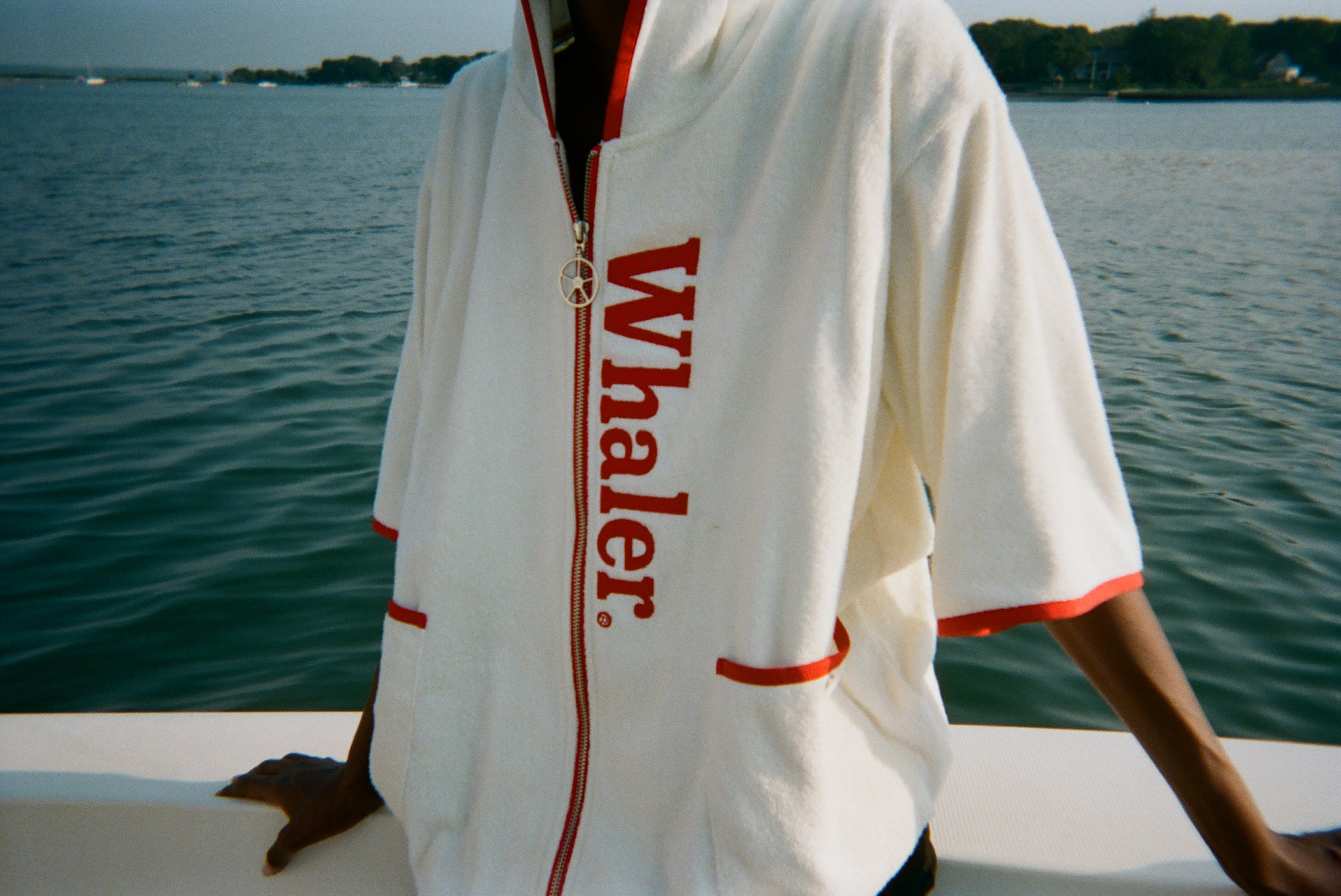 Close-up of woman wearing the white hooded beach towel top with red trim and vertical 'Whaler' text.