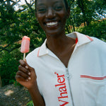 Woman wearing the white terry 'Whaler' Cabana, holding a popsicle and has a smile on her face. 
