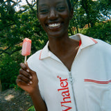 Woman wearing the white terry 'Whaler' Cabana, holding a popsicle and has a smile on her face. 