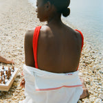 Woman sitting on beach with her back to us, the 'Boston Whaler' Cabana is wrapped around her. 