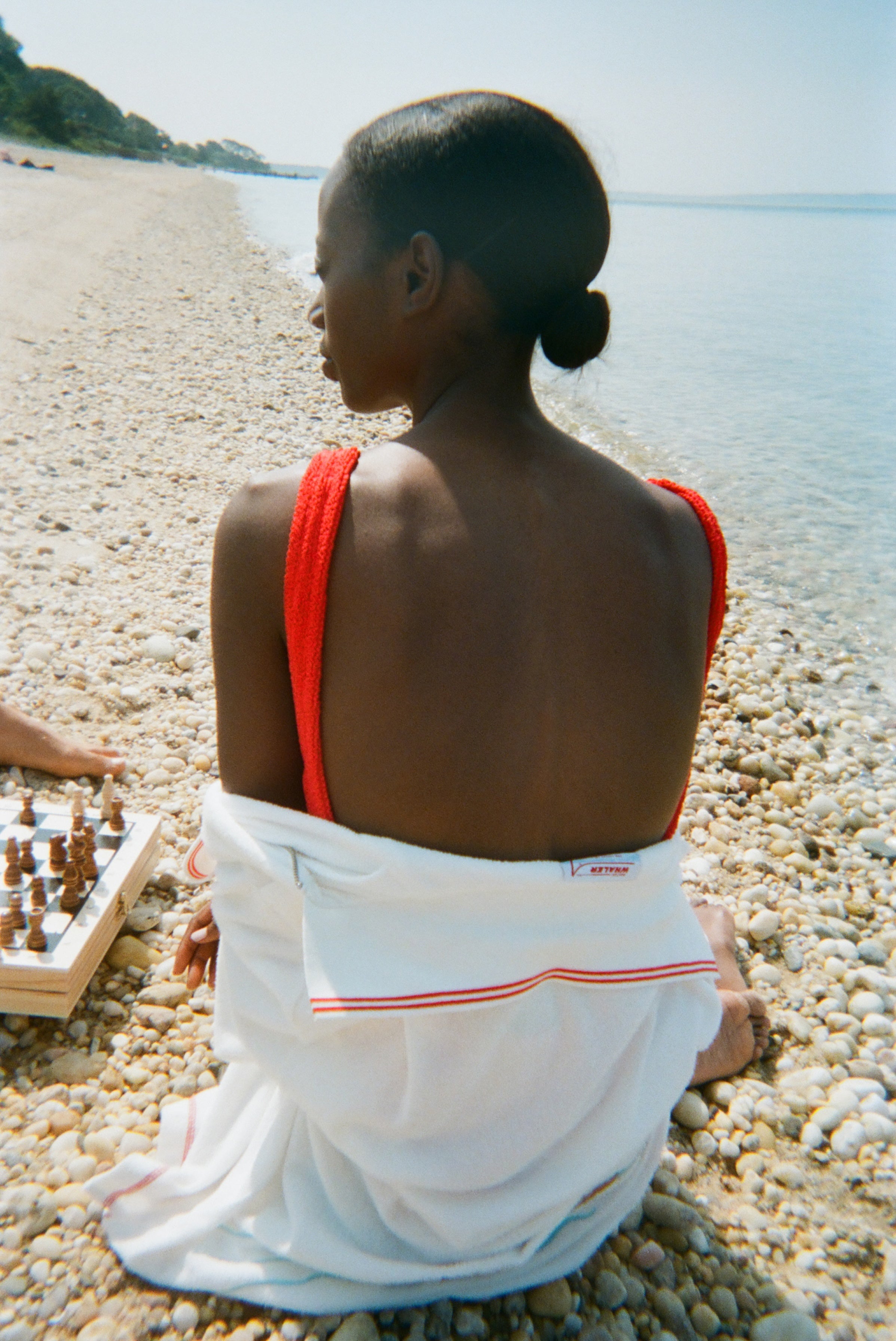 Woman sitting on beach with her back to us, the 'Boston Whaler' Cabana is wrapped around her. 