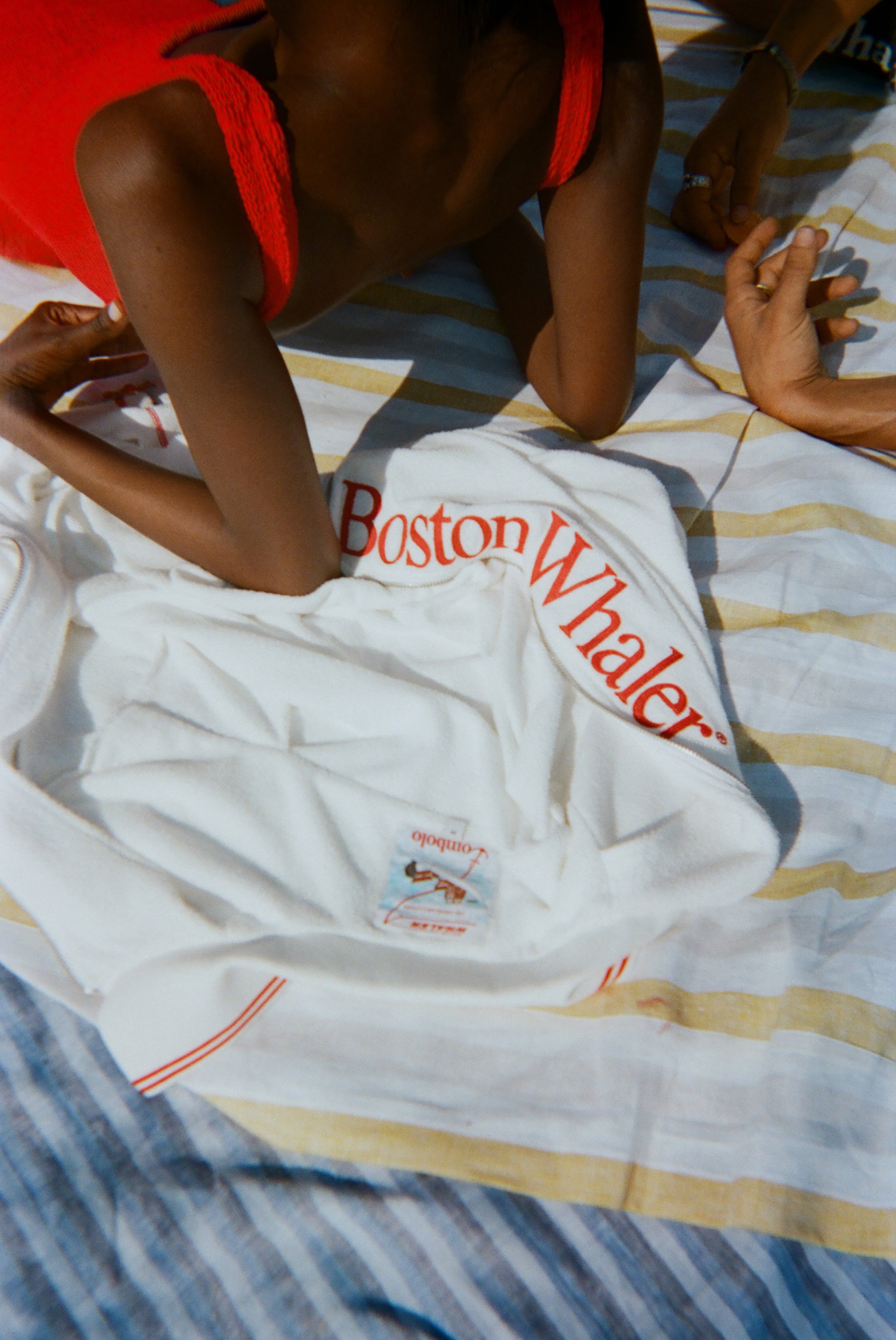Woman lying back on the 'Boston Whaler' Cabana, which is laid out on a striped towel.