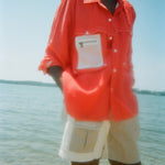 Woman in ocean water wearing the two-toned pleated 'Boston Whaler' shorts and a 'Boston Whaler' red vented fishing shirt.