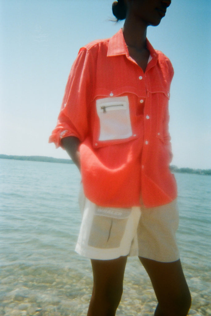 Woman in ocean water wearing the two-toned pleated 'Boston Whaler' shorts and a 'Boston Whaler' red vented fishing shirt.