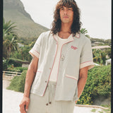 man wearing linen oyster shirt at the beach staring at camera