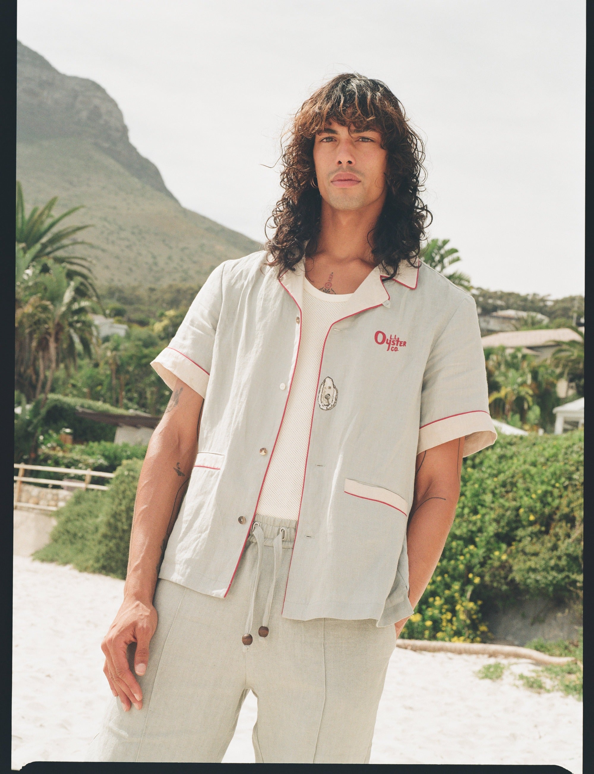 man wearing linen oyster shirt at the beach staring at camera