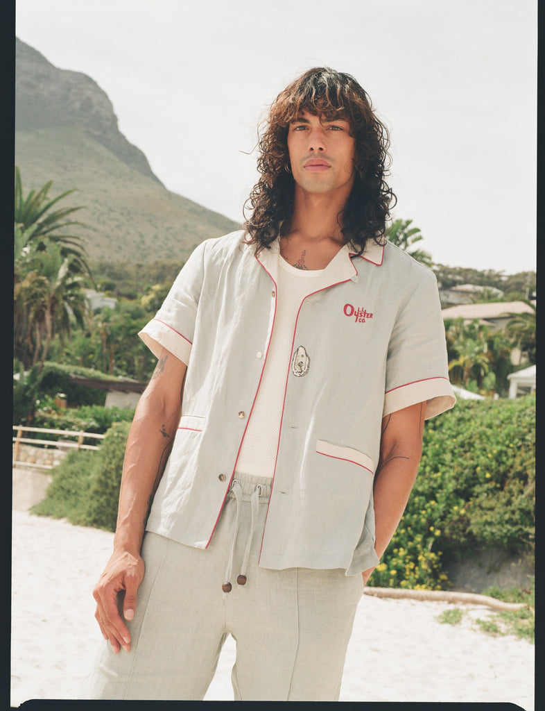 man wearing linen oyster shirt at the beach staring at camera