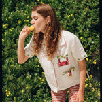 Woman eating ice cream leaning forward against hedge backdrop
